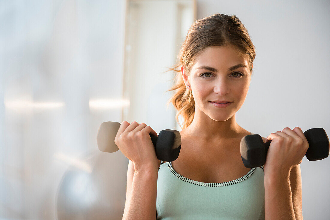 Gemischtrassige Frau hebt Gewichte im Fitnessstudio