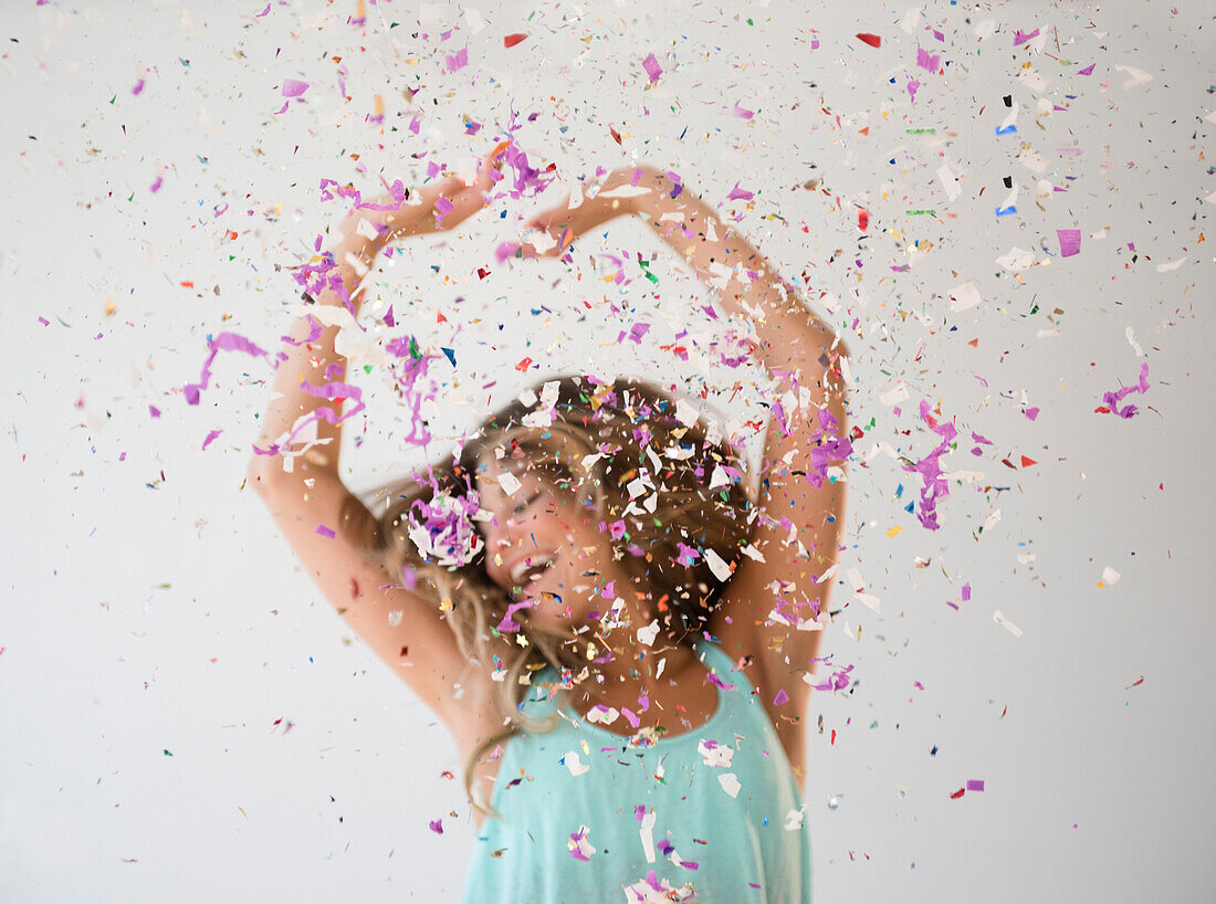 Mixed race woman playing in confetti