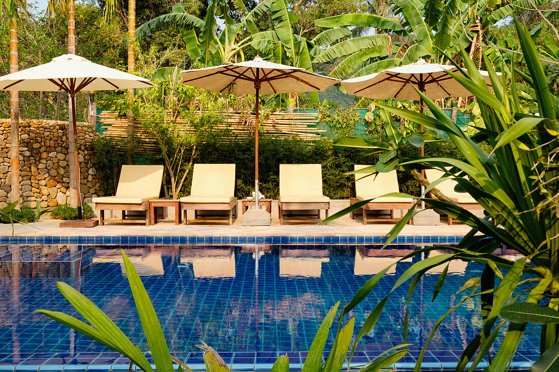 Empty lawn chairs by swimming pool