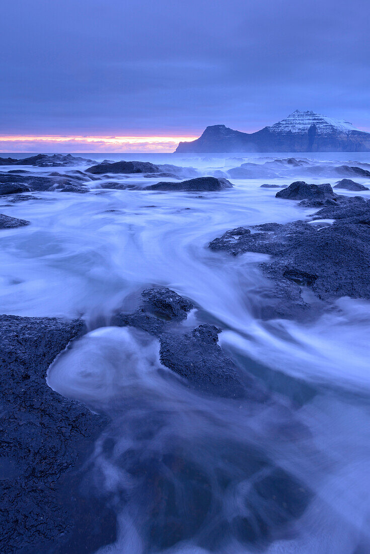 Surging waves rush over the basalt ledges of Gjogv at dawn, Eysturoy, Faroe Islands, Denmark, Europe
