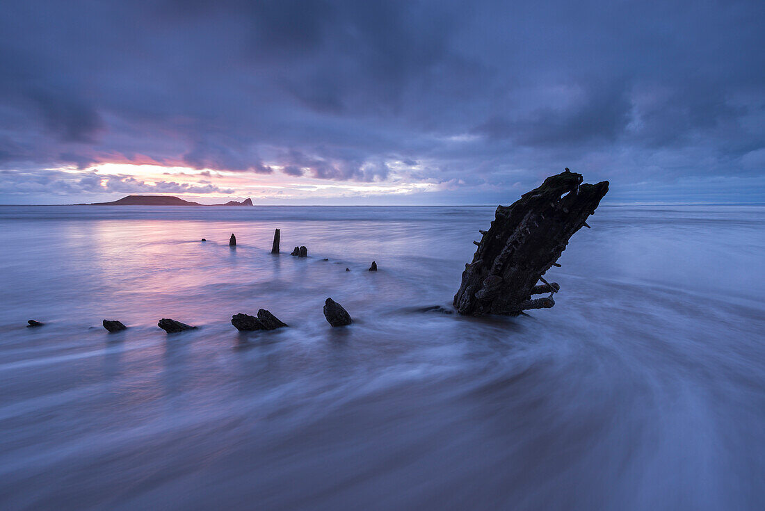 Shipwreck of the Helvetia on Rhossili Beach, looking towards Worms Head at sunset, Rhossili, Gower, Wales, United Kingdom, Europe