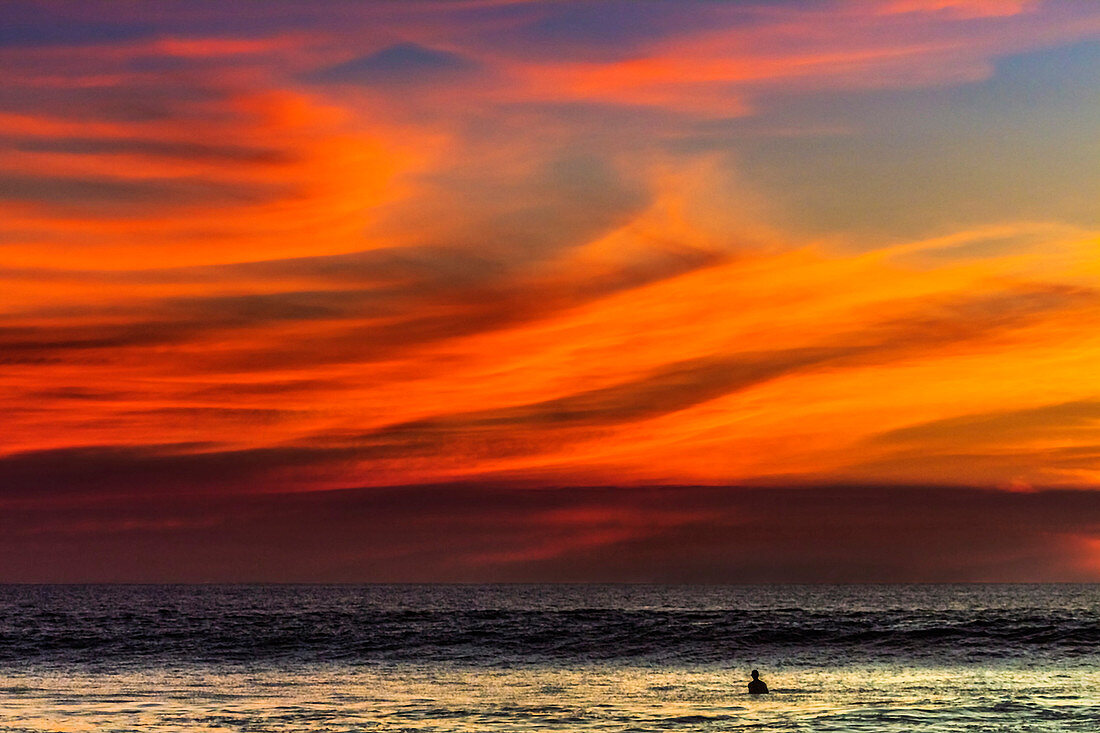 Lone surfer and sunset clouds off Playa Hermosa surf beach, southern Nicoya Peninsula, Santa Teresa, Puntarenas, Costa Rica, Central America