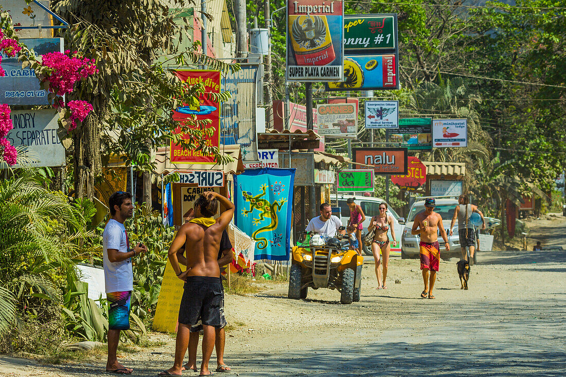 Tourists and signs on the main strip at this busy south coast of Nicoya Peninsula resort, Santa Teresa, Puntarenas, Costa Rica, Central America