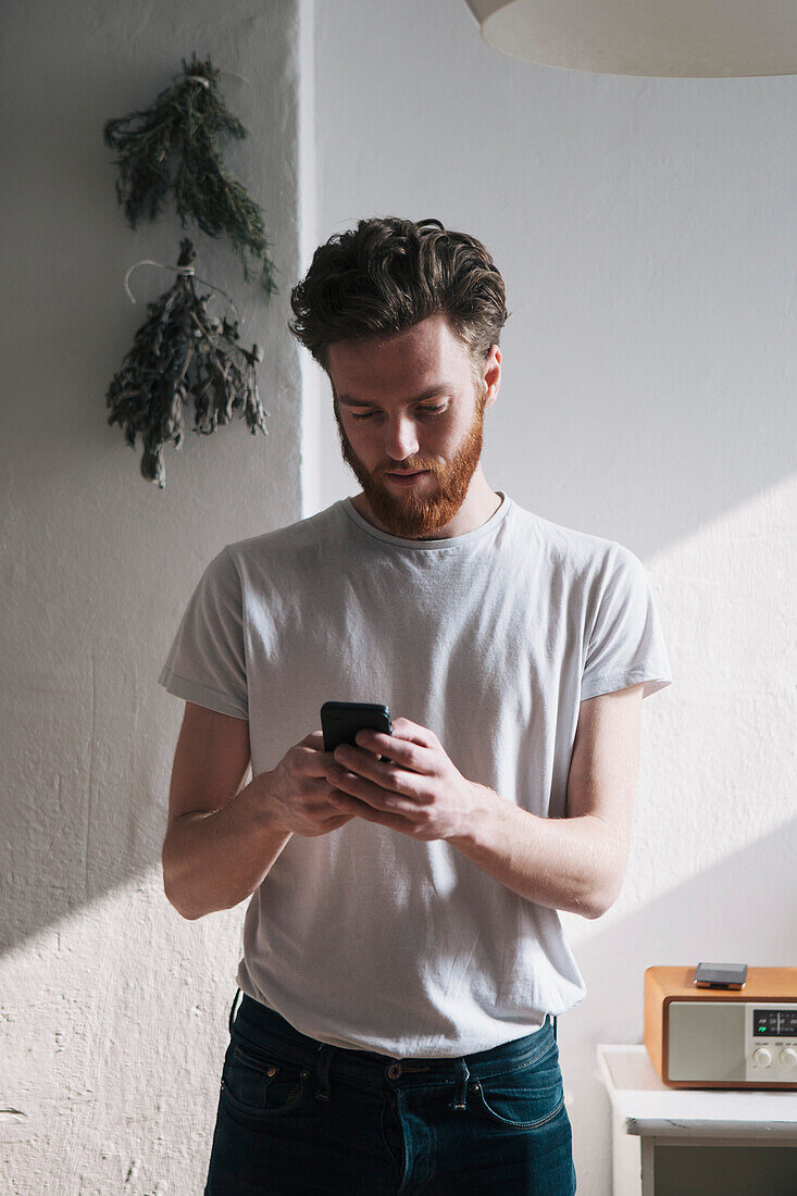 Young man using mobile phone at home