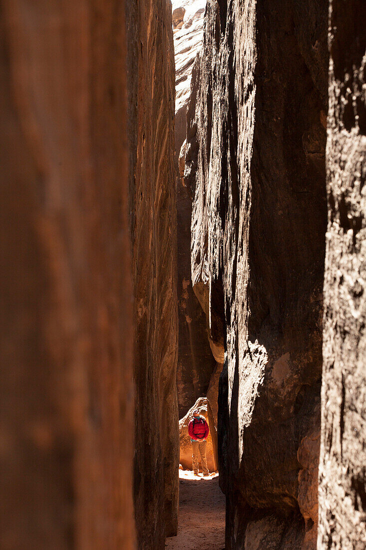 A woman hikes through a slot canyon in the Chesler Park are of Canyonlands National Park near Moab, Utah.