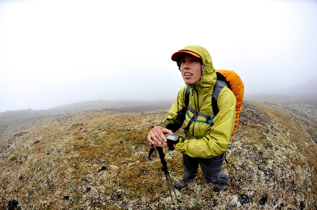 Female hiker navigates the flanks of Homocide with a gps in the front range of the Chugach Mountains in Anchorage, Alaska August 2011.