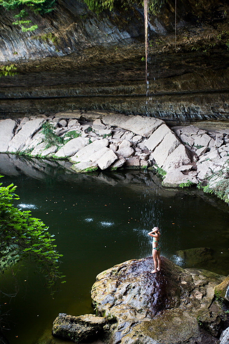 A young woman enjoys the Hamilton Pool near Wimberley, Texas on a hot day.