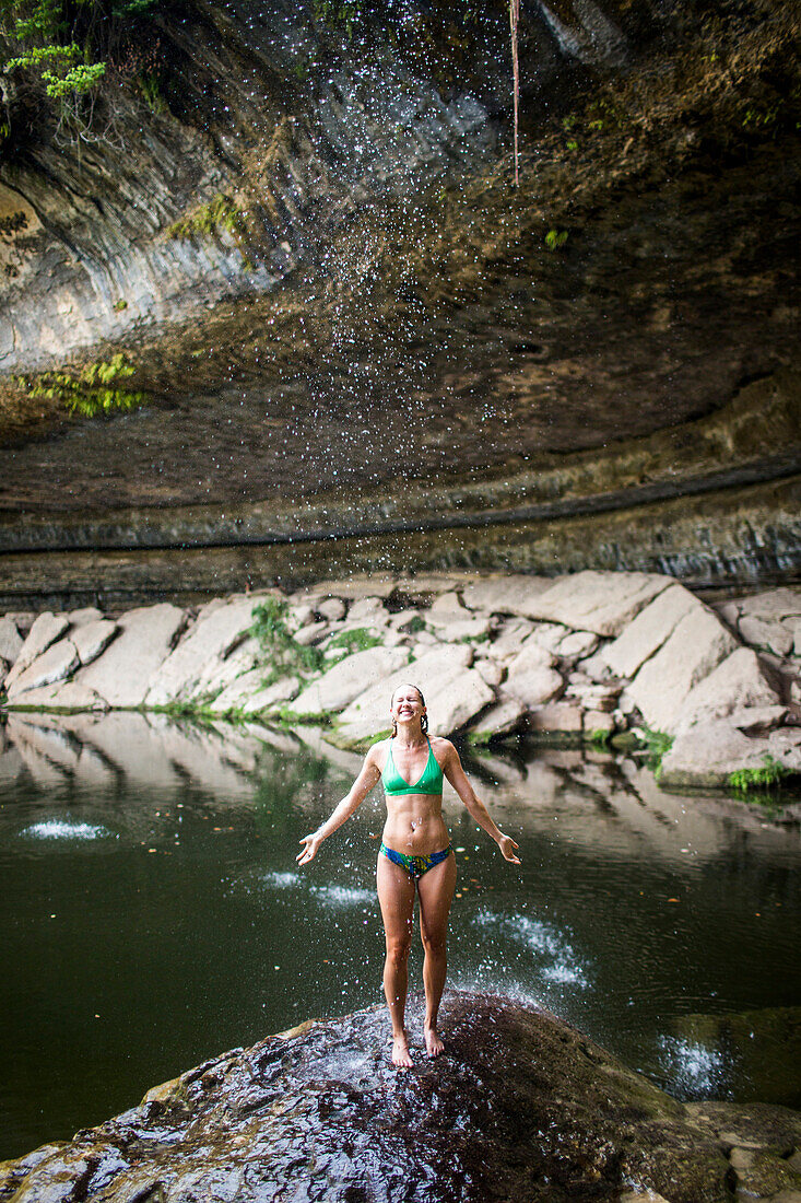 A young woman enjoys the Hamilton Pool near Wimberley, Texas on a hot day.