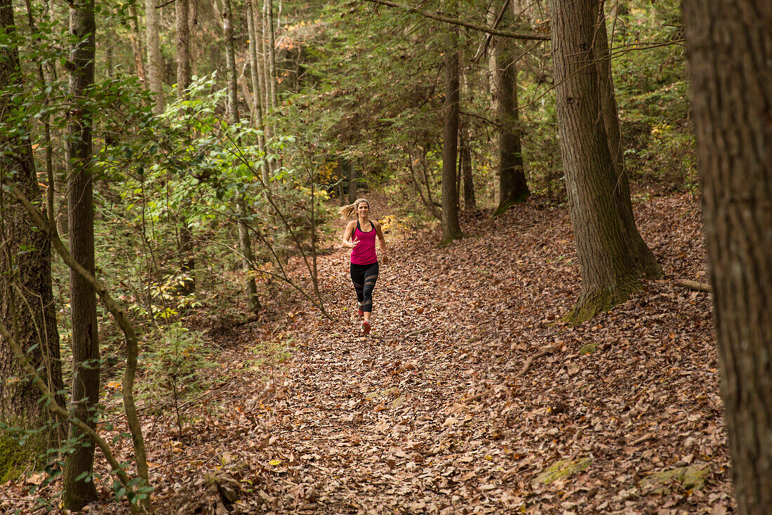 A young blonde woman runs on a trail in the forest in the fall in Tennessee