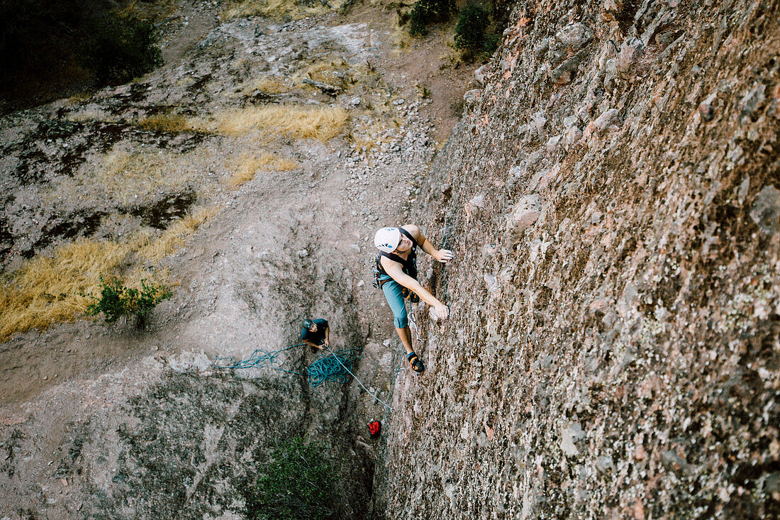 'A man leading ''Kibbles and Bits'' on the Flumes Formation in Pinnacles National Park'
