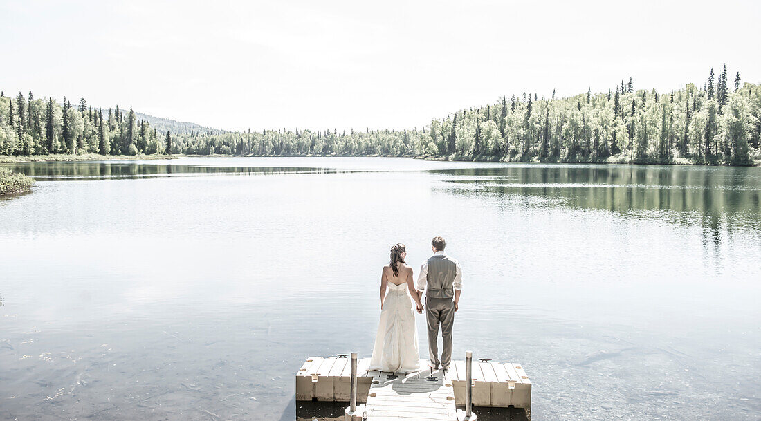 Bride and groom stand on a dock at X-Y Lake in Talkeetna, Alaska.