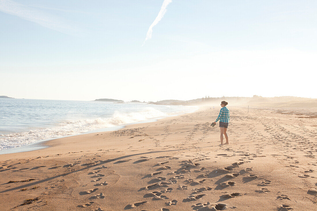 Woman walking along beach at Reid State Park