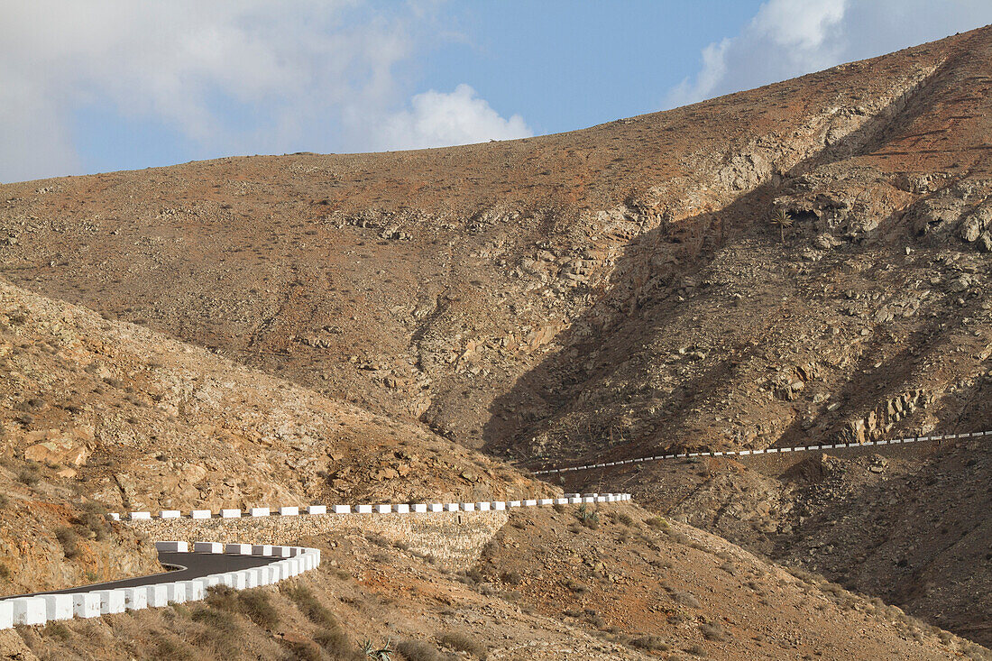 Empty winding road in the middle of a desert and volcanic landscape