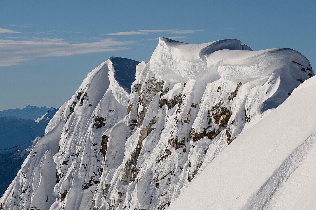 A mountain ridge holds heavy cornices from winter storms.