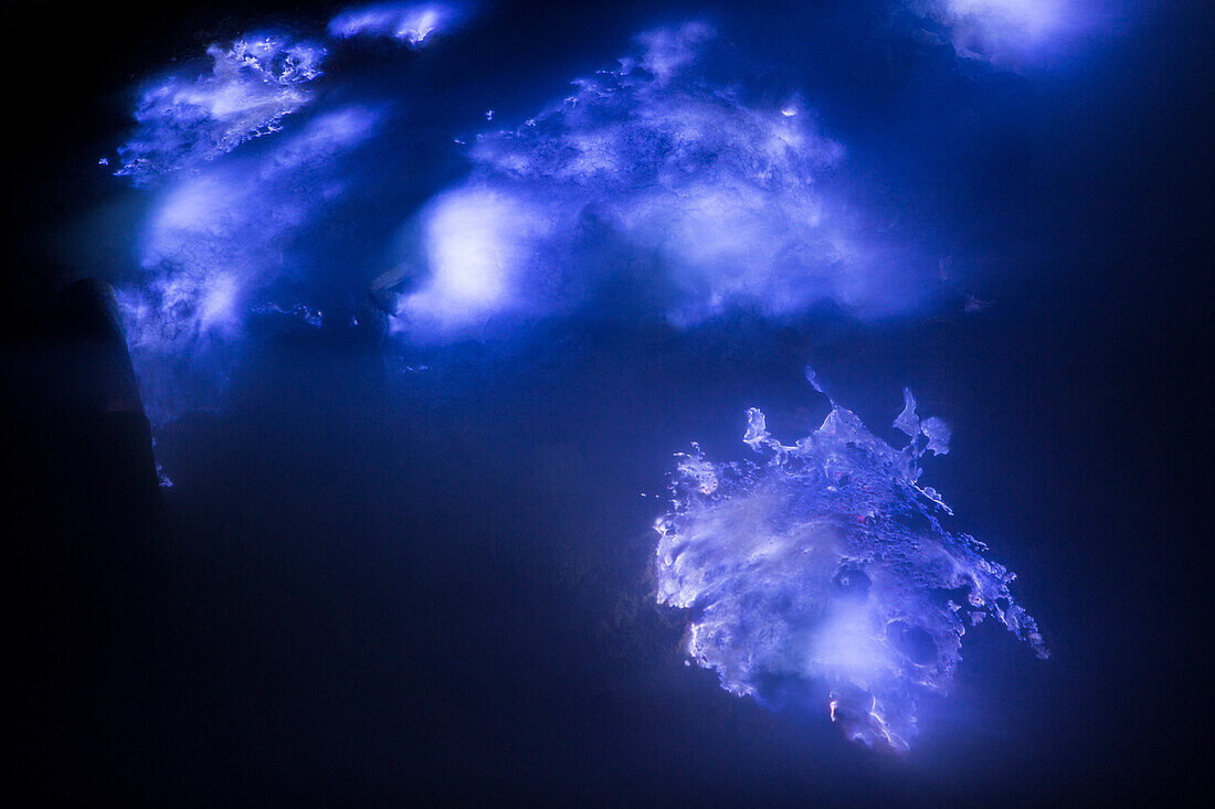 Blue flames of molten sulfur burning at the mine inside the crater of Kawah Ijen volcano, Banyuwangi, Java, Indonesia