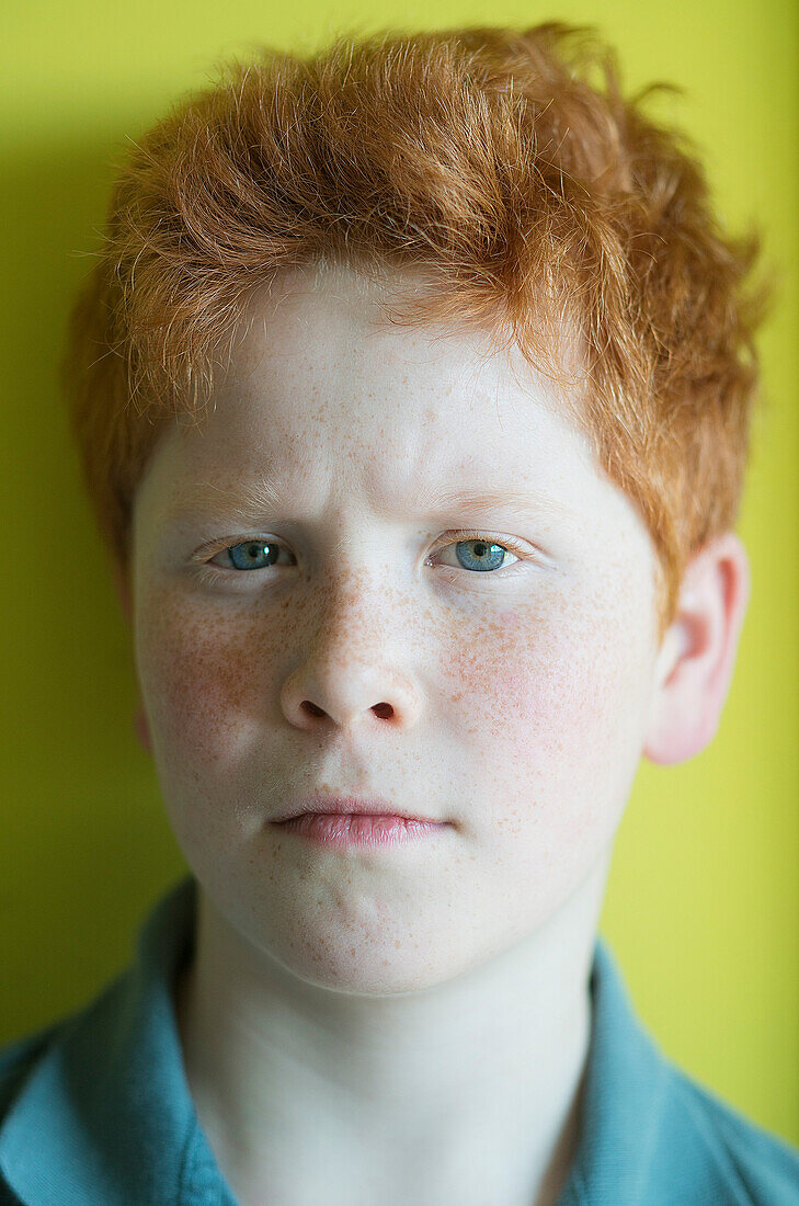 Boy with red hair furrowing brow, portrait