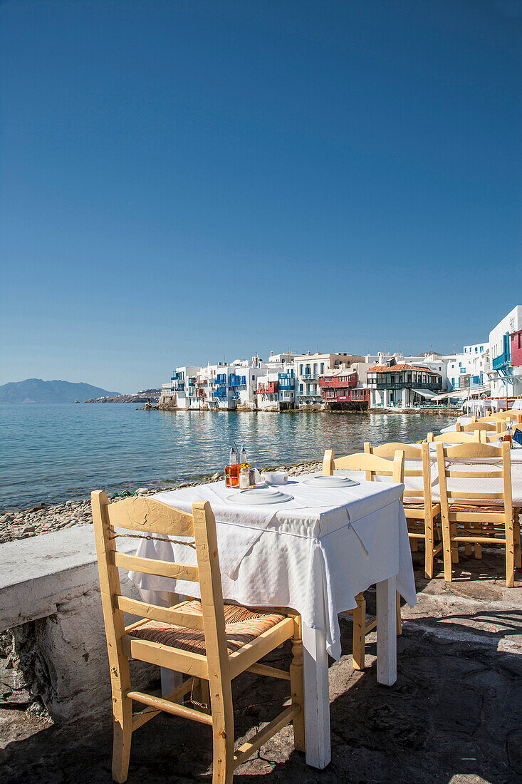 Tables at waterfront cafe under blue sky