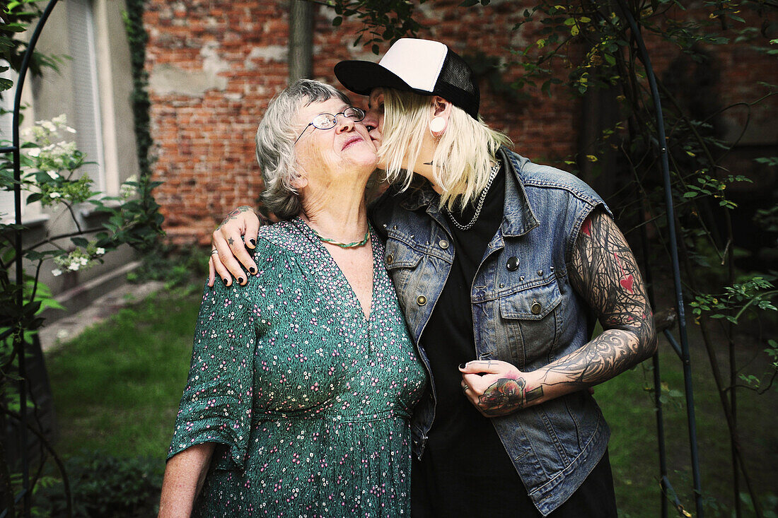 Daughter kissing mother while standing in back yard