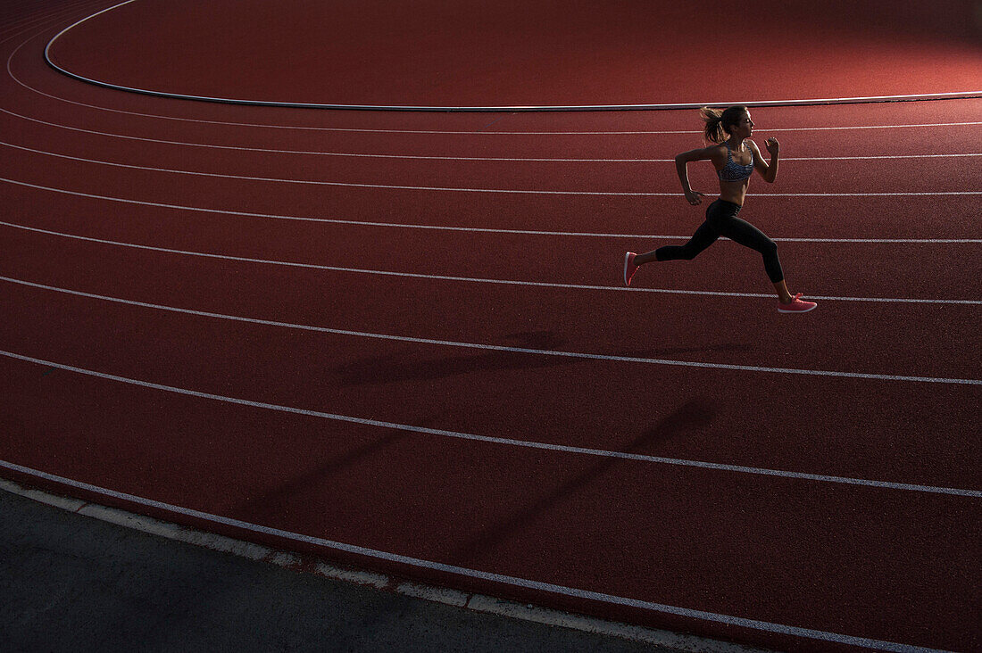 High angle view of young female athlete running on race track