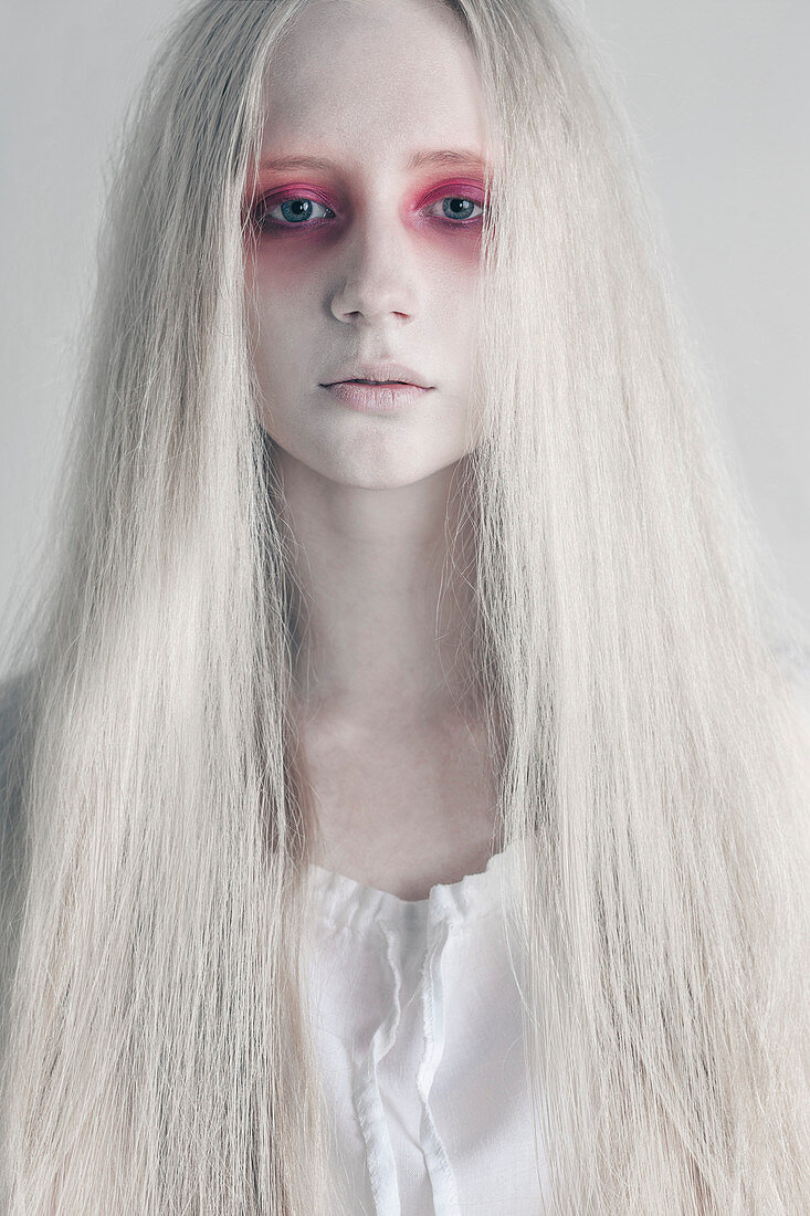 Junge Frau mit unheimlichen roten Augen und langen Haaren vor weißem Hintergrund