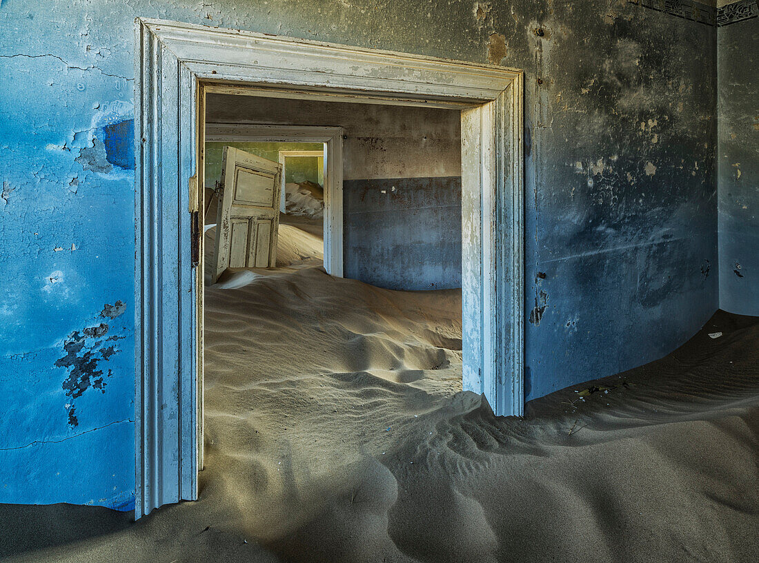 Drifting sand fills the rooms of a colourful abandoned house Kolmanskop, Namibia