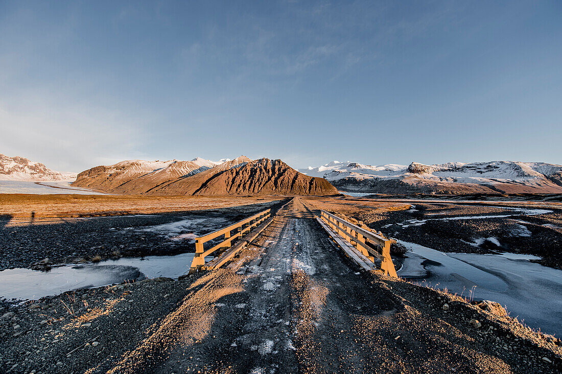Unbefestigte Straße und Brücke bei Sonnenuntergang, Gletscher Vatnajökull, Winter, Kalt, Island