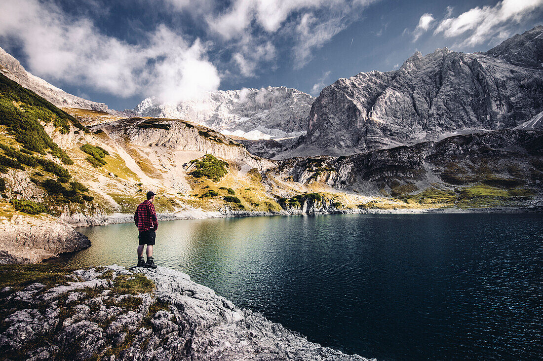Wanderer at lake Drachensee beneath the Coburger Hut, Mieminger Range, Zugspitz area, Alps, Tyrol, Austria