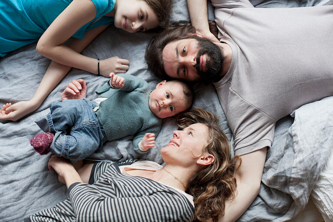 High angle view of family relaxing on bed