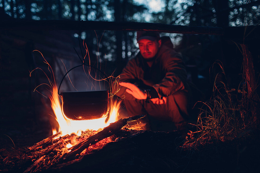 Mid adult man warming hands at campsite