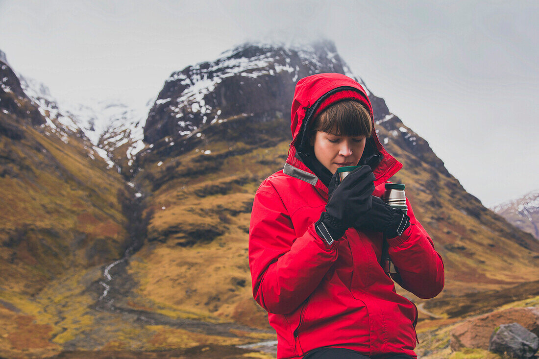 Woman drinking coffee against mountain during winter