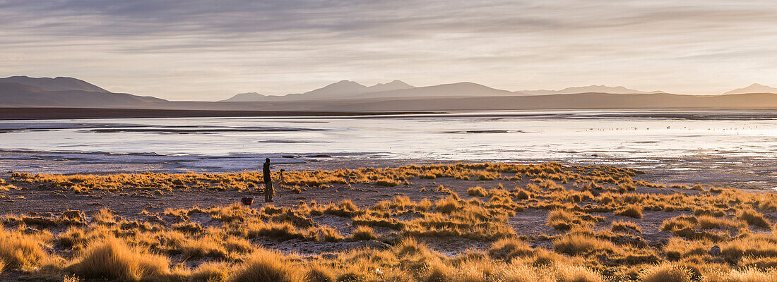 Photographer taking a photo at sunrise at Chalviri Salt Flats Salar de Chalviri, Altiplano of Bolivia, South America