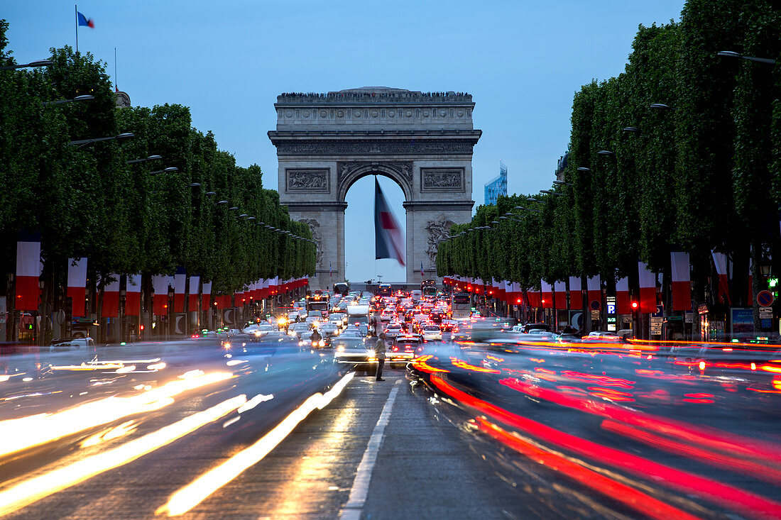 View down the Champs Elysees to the Arc de Triomphe, illuminated at dusk, Paris, France, Europe