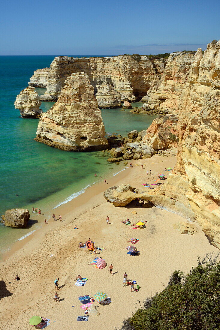Overview of tourists on beach, sandstone cliffs and seastacks at Praia da Marinha, near Carvoeiro, Algarve, Portugal, Europe