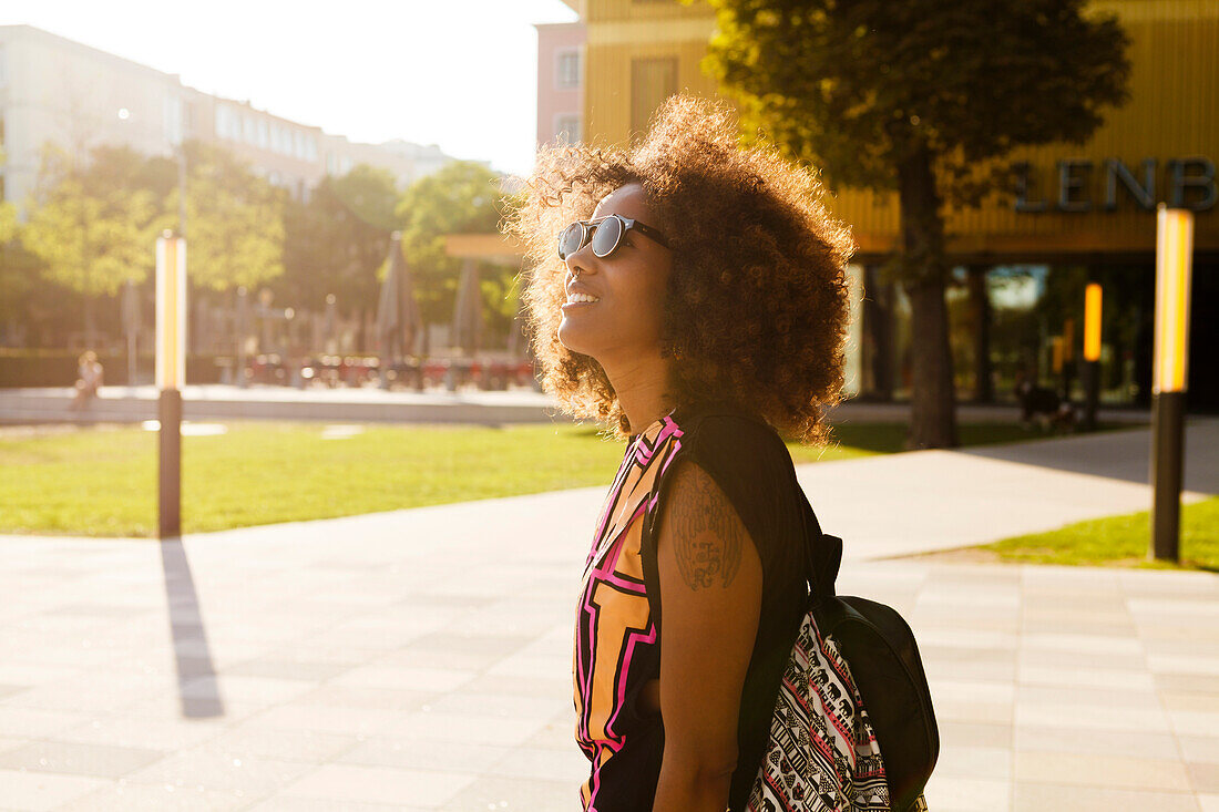 Junge, afroamerikanischen Frau mit Rucksack am Lenbachplatz, München, Bayern, Deutschland