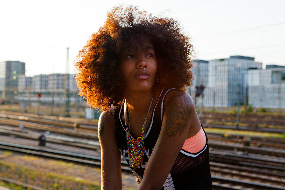 Portrait einer jungen afroamerikanischen Frau  in moderner urbaner Szenerie mit Gleisen , Hackerbrücke, München, Bayern, Deutschland