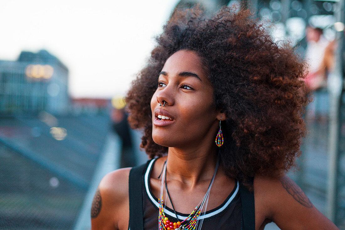 Young afro-american woman walking on a old steel bridge in urban scenery, Hackerbruecke bridge, Munich, Bavaria, Germany