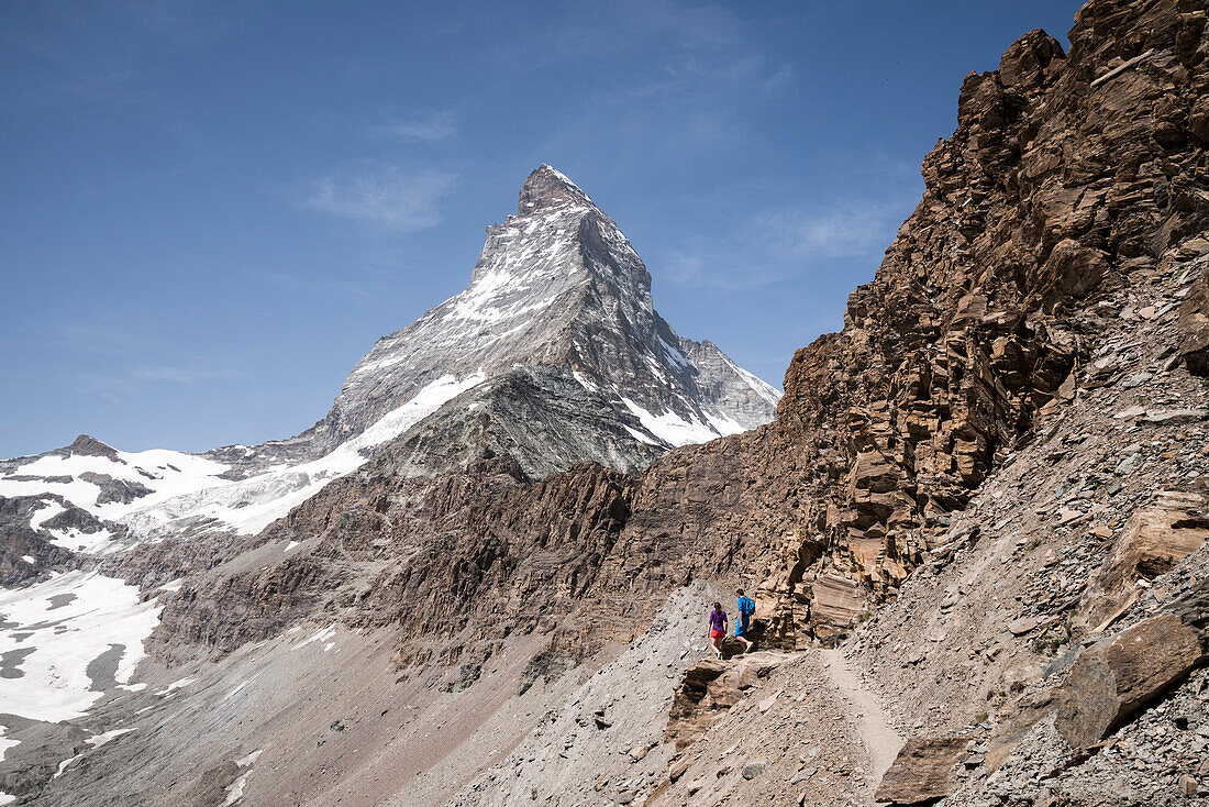 Two hikers on their way to the Hörnli Hut, in the background the Matterhorn, Pennine Alps, canton of Valais, Switzerland