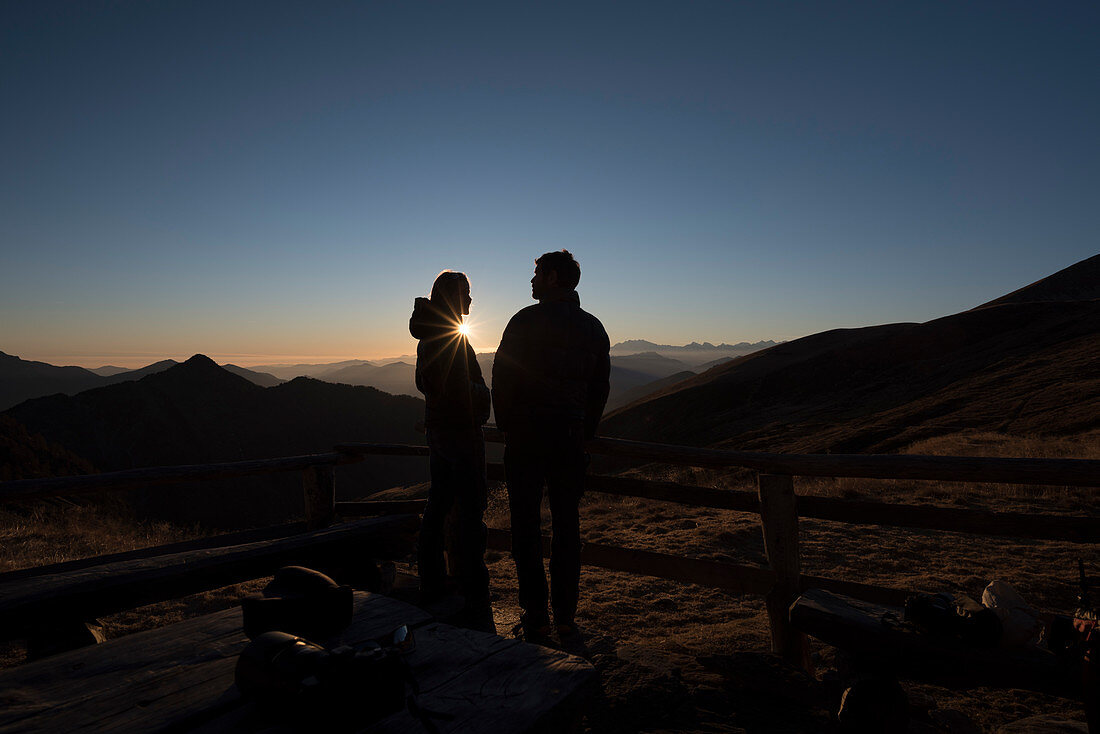 A couple in front of the Borgna Hut at sunset, Val Verzasca, Lepontine Alps, canton of Ticino, Switzerland