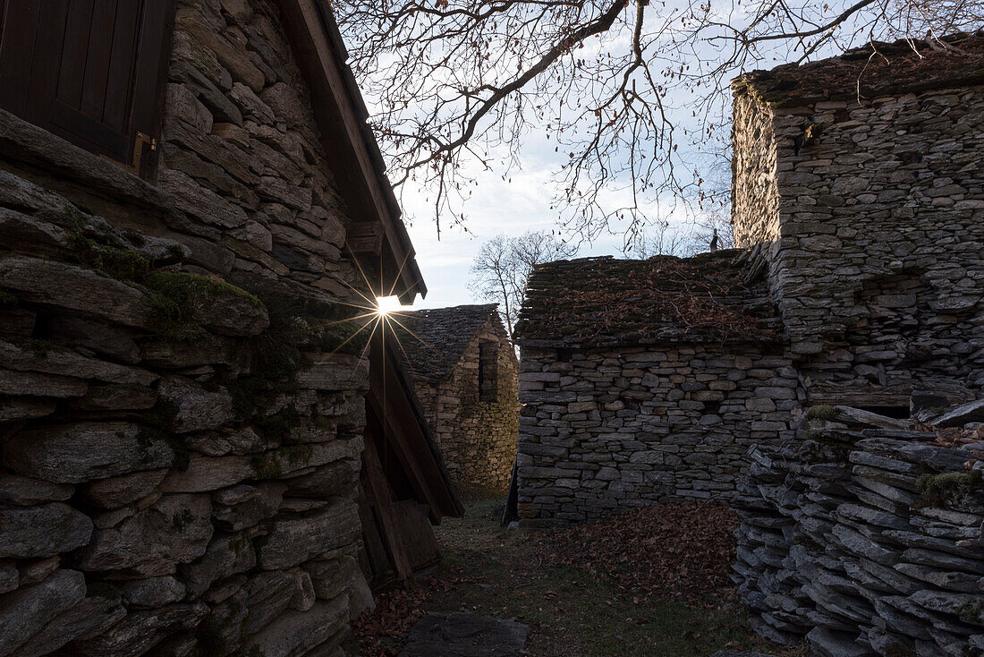 The last sunlight of the day shines through the houses of the alp Bazzadee, canton of Ticino, near Locarno, Switzerland