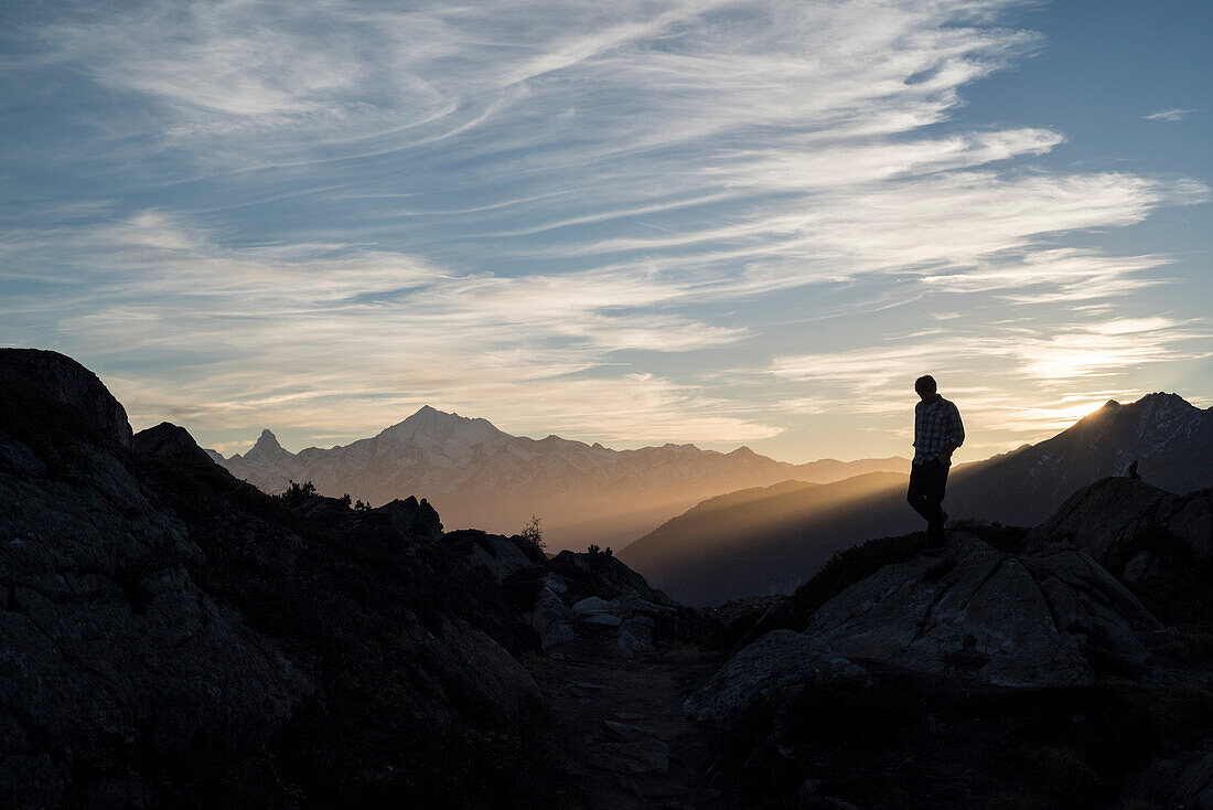A hiker near Bettmeralp, in the background Matterhorn and Weisshorn, Bernese Alps, canton of Valais, Switzerland