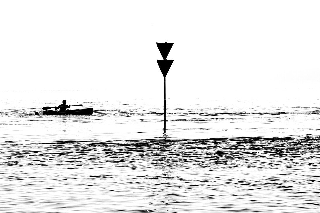 Silhouette, a canoeist passes a navigational sign on the Elbe, Hamburg, Germany