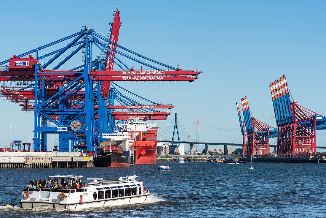 A excursion boat entering the harbour, container terminal Burchardkai, with many container cranes, some vessels and the Köhlbrandbrücke in the background, Hamburg, Germany