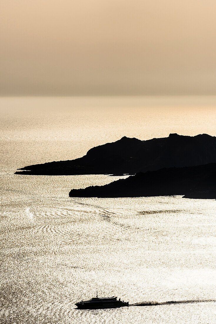Die Fähre zwischen den Kykladen Inseln im Sonnenuntergangslicht vor Santorini, Griechenland