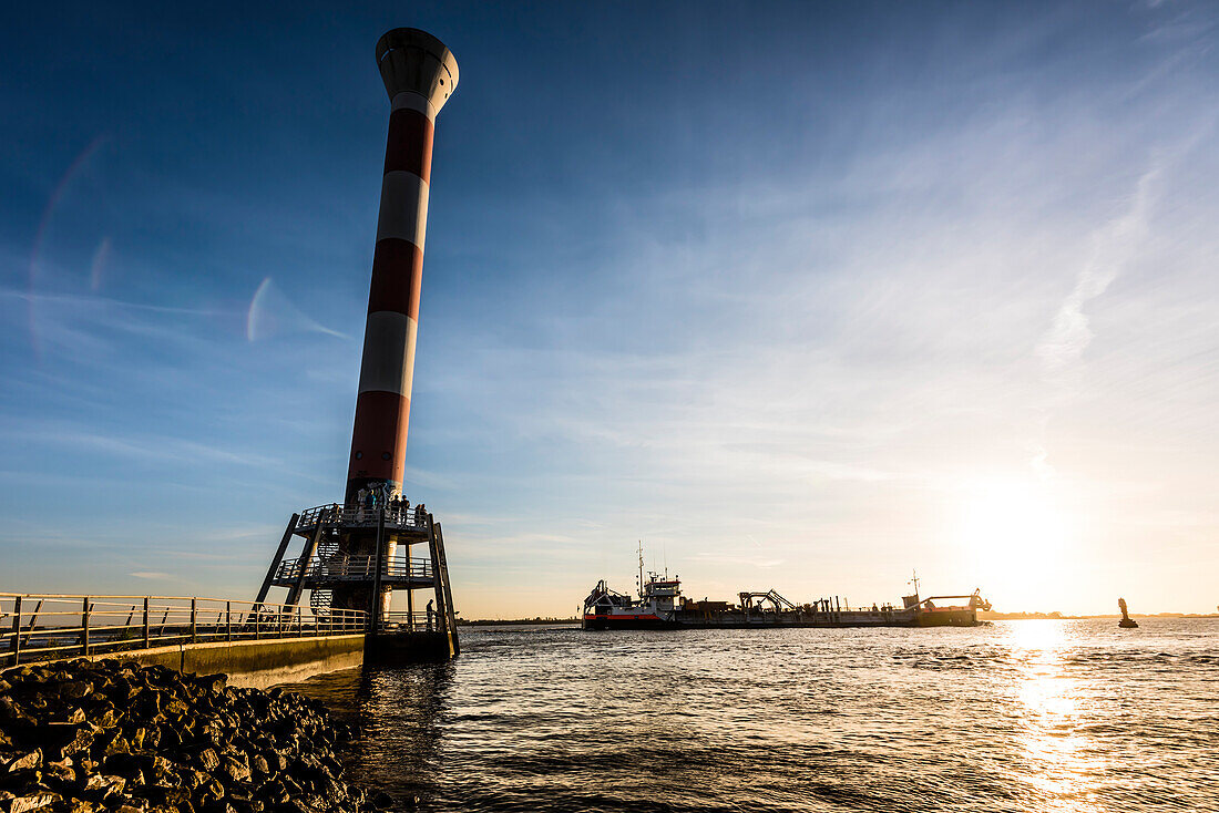 ' A dredger passes the lighthouse  ''Unterfeuer Blankenese'' (42 m high) at sunset, Blankenese, Hamburg, Germany'