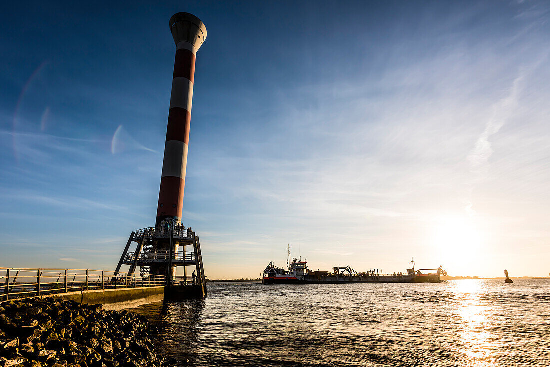 'Ein Baggerschiff passiert den Leuchtturm ''Unterfeuer Blankenese'' (42m hoch) bei Sonnenuntergang, Blankenese, Hamburg, Germany '