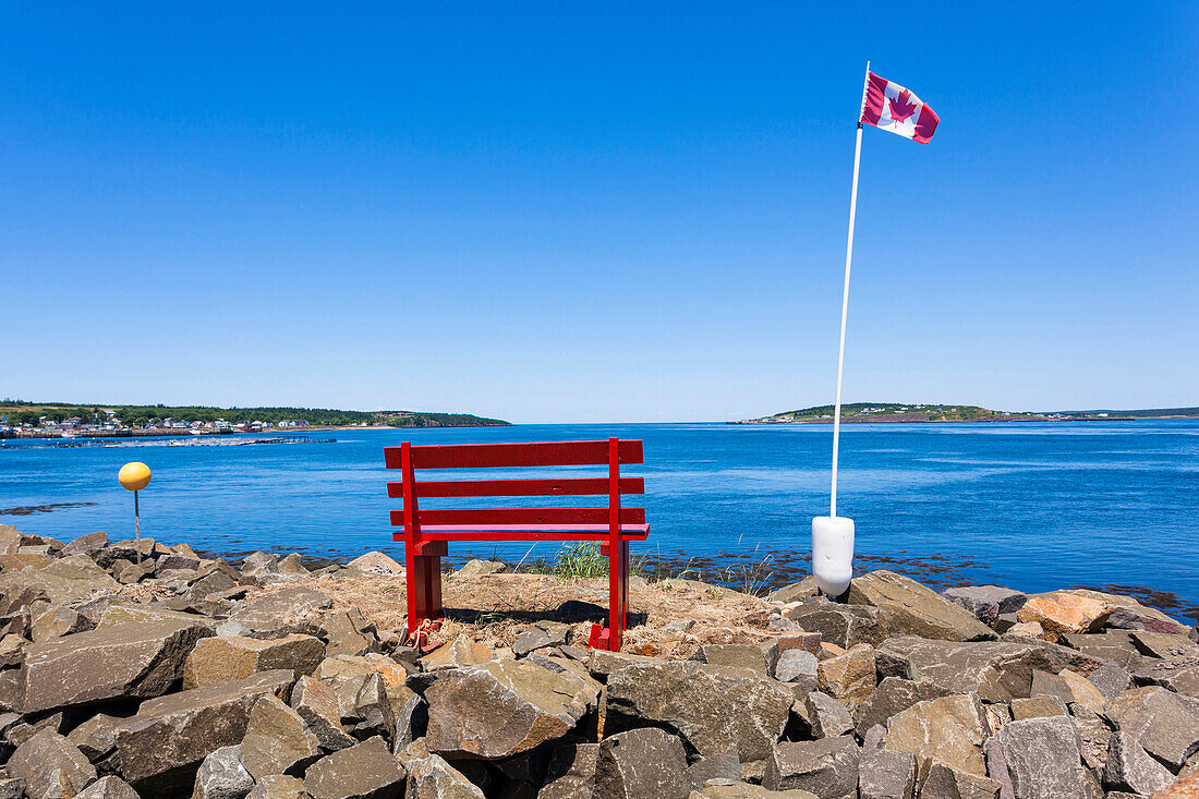 Ein ruhiger Platz mit roter Bank und kanadischer Nationalflagge am Nordatlantischen Ozean, Digby, Nova Scotia, Kanada