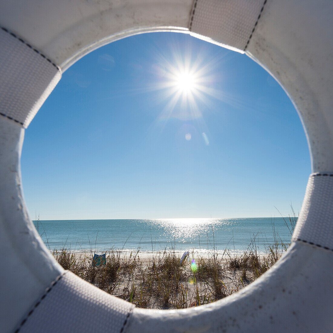 View through a lifebelt at a lonesome beach during sunshine at the golf of Mexico, Naples, Florida, USA