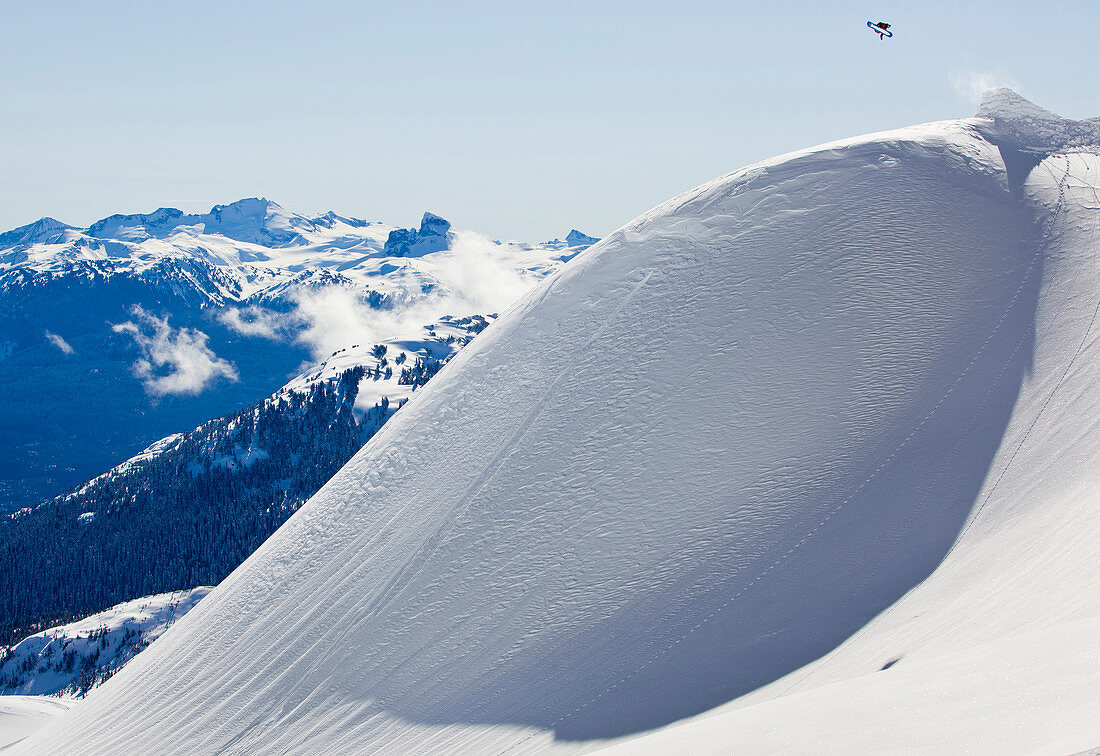 A man hits a classic jump on his snowboard in the Whistler backcountry.