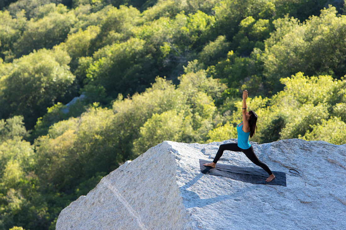 A women performs yoga on a rock outcrop in Little Cottonwood Canyon, Utah.