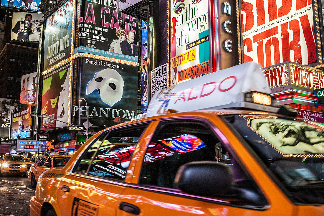 A yellow taxi drives through bright, busy Times Square, NYC